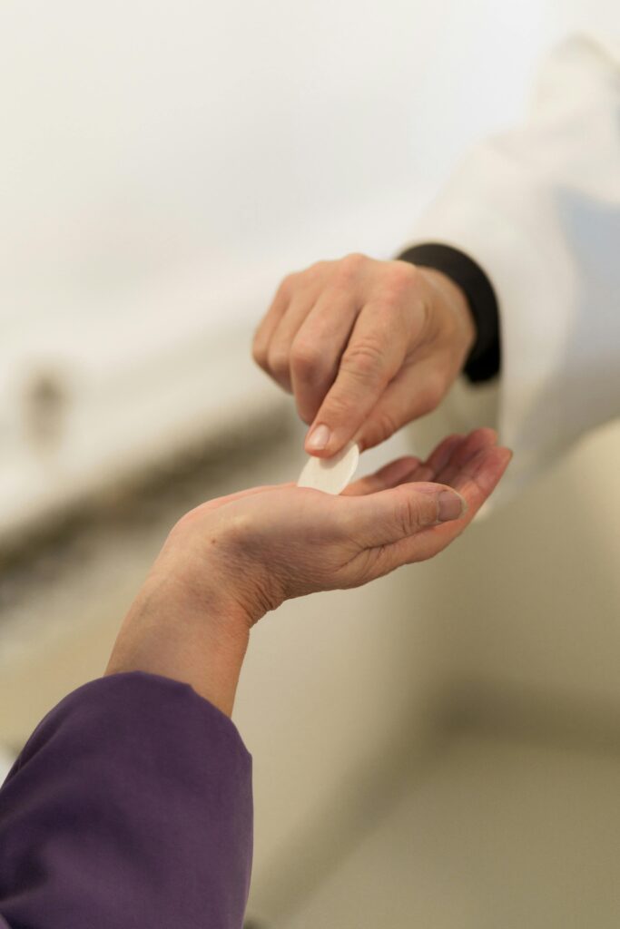 A pastor hands communion bread to a parishioner, capturing a sacred religious ritual.